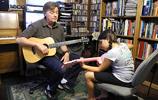 Photo of a beginning guitar lesson.